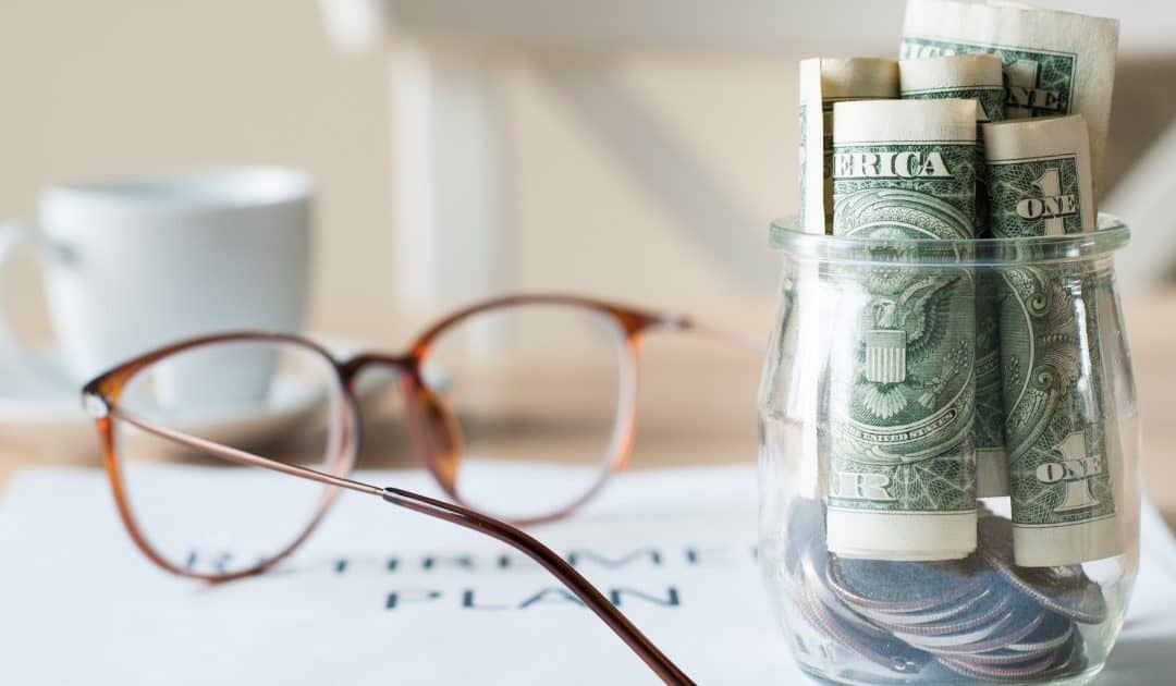 Glasses, coffee mug, retirement plan and jar of dollar bills on a table